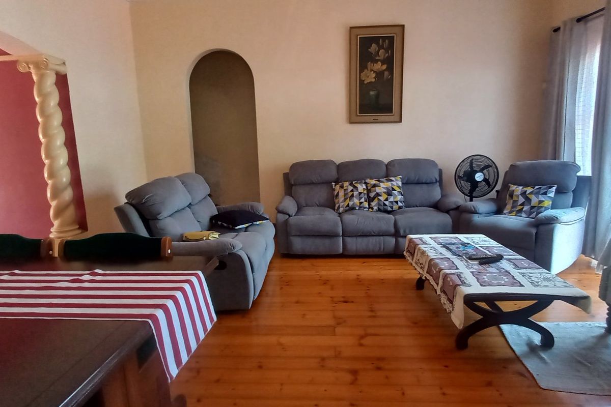 Spacious living area featuring warm hardwood flooring, an arched architectural detail, and a decorative column, providing a comfortable and inviting atmosphere.