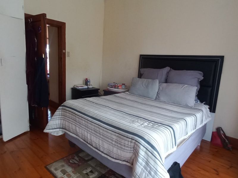 A bedroom featuring original timber flooring and built-in cupboards, offering a functional space with potential for cosmetic updates.