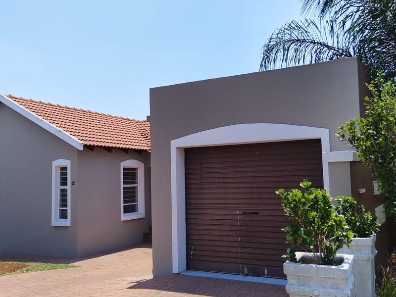 Front view of the property featuring a paved driveway, a single roller garage door, and a tiled roof.