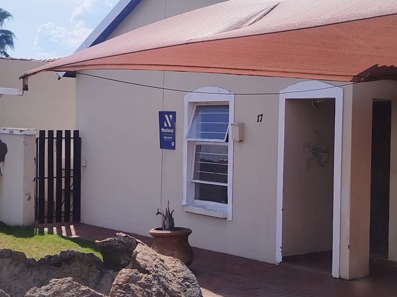Front exterior view of the house featuring a paved entrance, shade sail, and tiled roof.