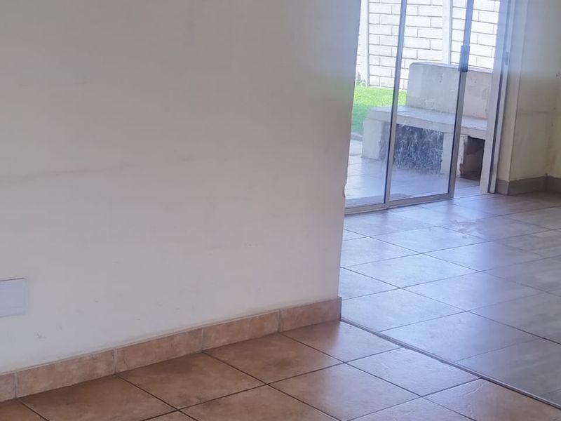 An open-plan living area featuring ceramic floor tiles and sliding glass doors that provide direct access to the rear patio and garden.