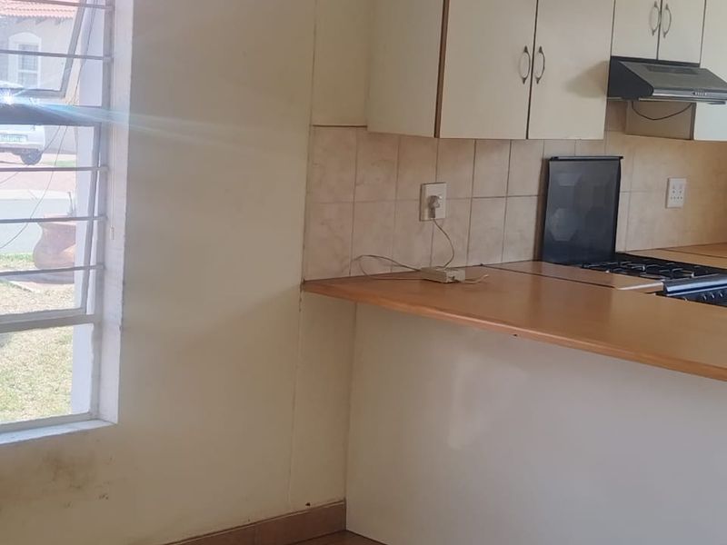 A functional kitchen area featuring built-in cabinetry, a wooden countertop, and tiled flooring, offering a practical layout for daily meal preparation.