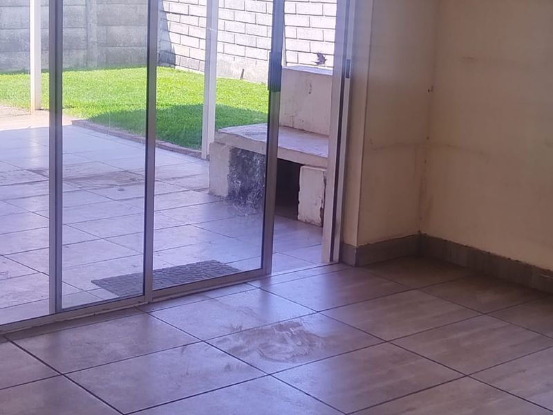 An interior living space featuring large sliding glass doors that open onto a paved patio area with a built-in outdoor bench.