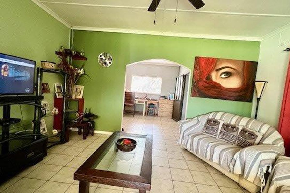 A living room featuring tiled flooring, a ceiling fan, and an arched entryway leading to an adjacent space.