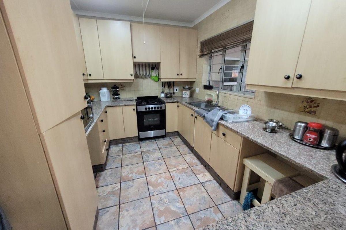 Functional kitchen featuring laminate cabinetry, granite countertops, built-in oven, gas hob, and tiled flooring with a practical U-shaped layout.