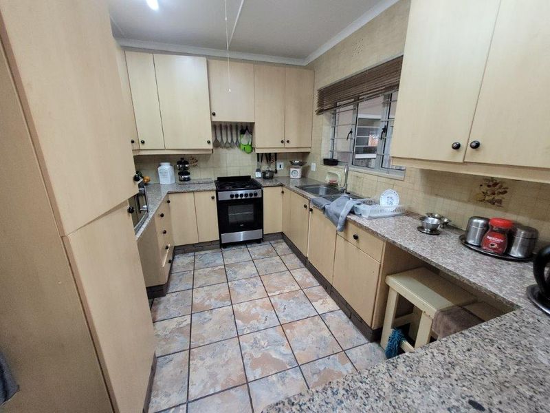 Functional kitchen featuring laminate cabinetry, granite countertops, built-in oven, gas hob, and tiled flooring with a practical U-shaped layout.