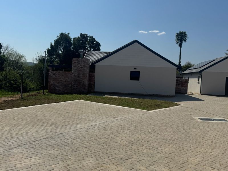 A view of the property exterior featuring a paved driveway, brick chimney, and modern roofline in a residential setting.