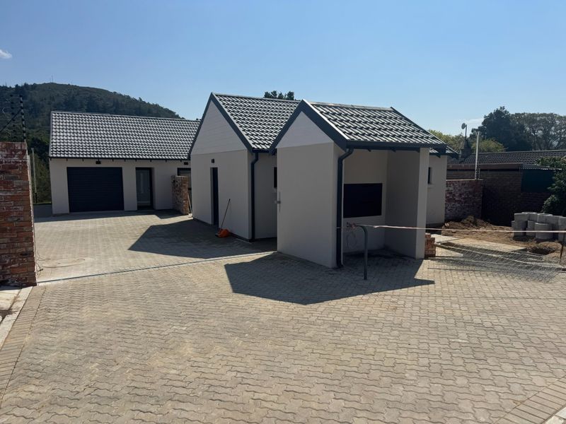 Front view of a modern residential property featuring a paved driveway, garage, and contemporary architectural design with tiled roofing.