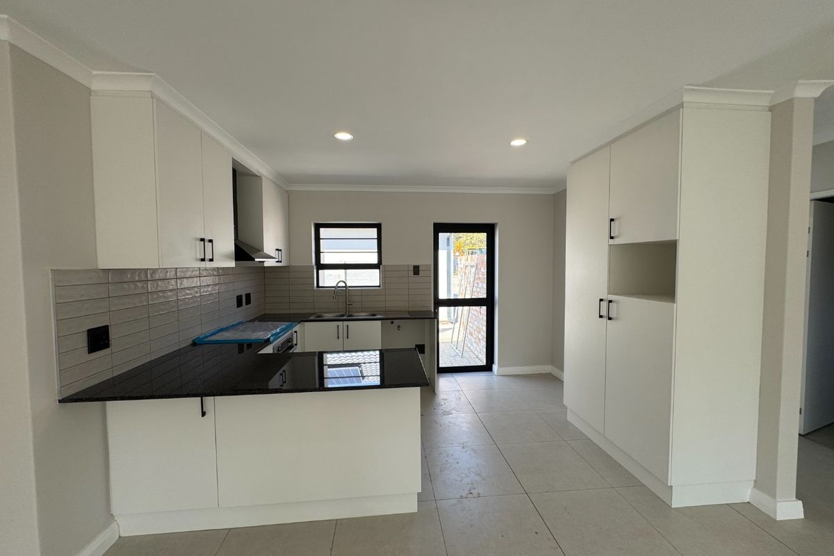 Modern kitchen featuring white cabinetry, dark granite countertops, subway tile backsplash, and tiled flooring with direct access to the exterior.