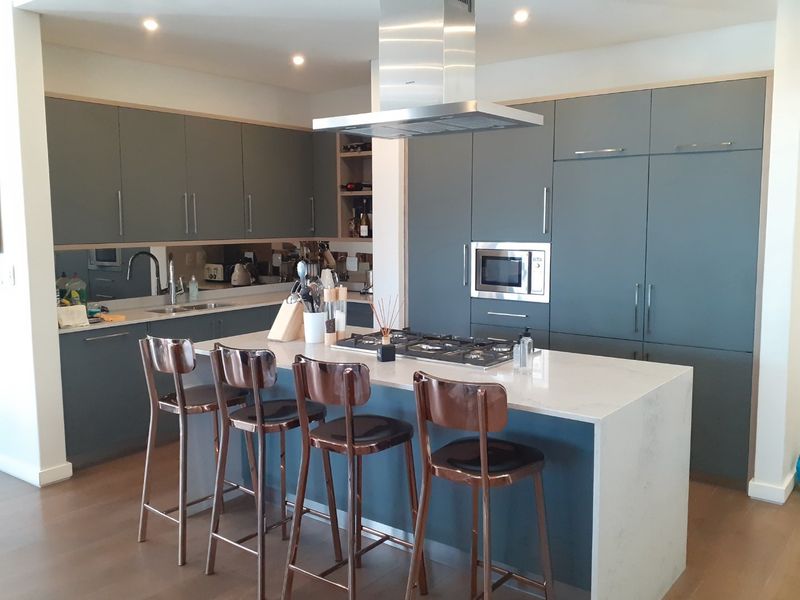Modern kitchen featuring a central island with a gas hob, integrated appliances, sleek cabinetry, and high-quality quartz countertops.