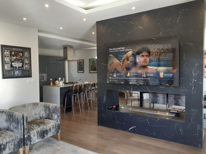Modern open-plan living area featuring a striking black marble feature wall with an integrated fireplace and a sleek, contemporary kitchen with an island.