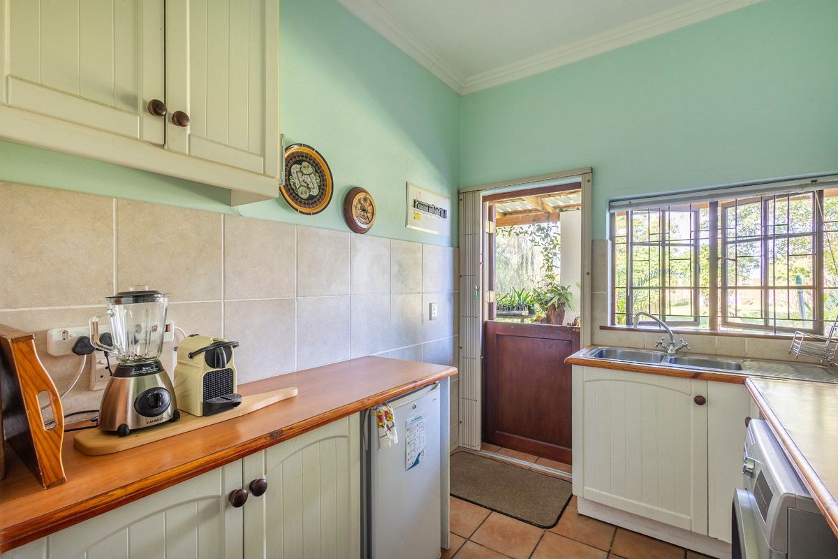 A functional kitchen featuring wooden countertops, built-in cabinetry, tiled backsplash, and direct access to the garden through a stable door.