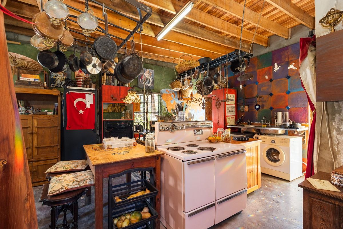 Rustic kitchen featuring exposed timber ceiling beams, a vintage stove, and functional cabinetry, offering a unique character with potential for modernization.