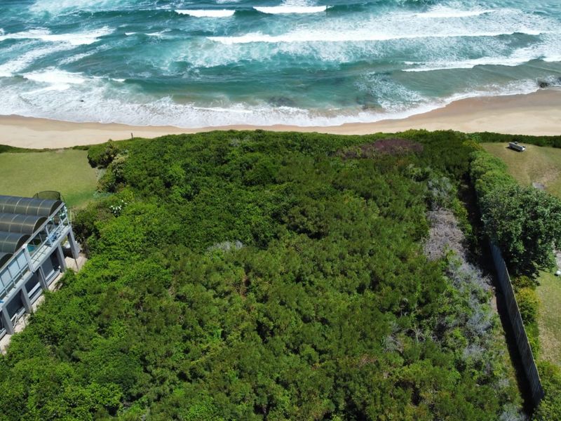 Aerial view of a vacant residential plot featuring direct ocean frontage and established coastal vegetation.