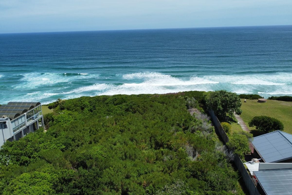 An aerial view of a vacant residential plot featuring coastal vegetation, direct ocean views, and established boundary fencing.