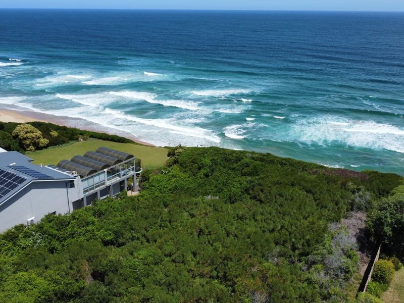 Aerial view of a coastal residential property featuring solar panels and an enclosed patio overlooking the ocean.