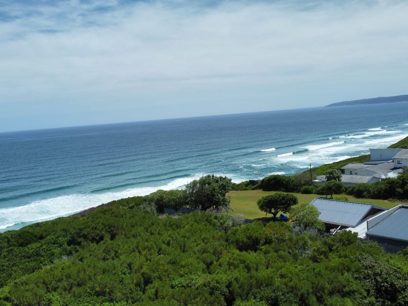 An aerial view of the coastal residential property, showcasing the surrounding landscape, lush vegetation, and proximity to the ocean.