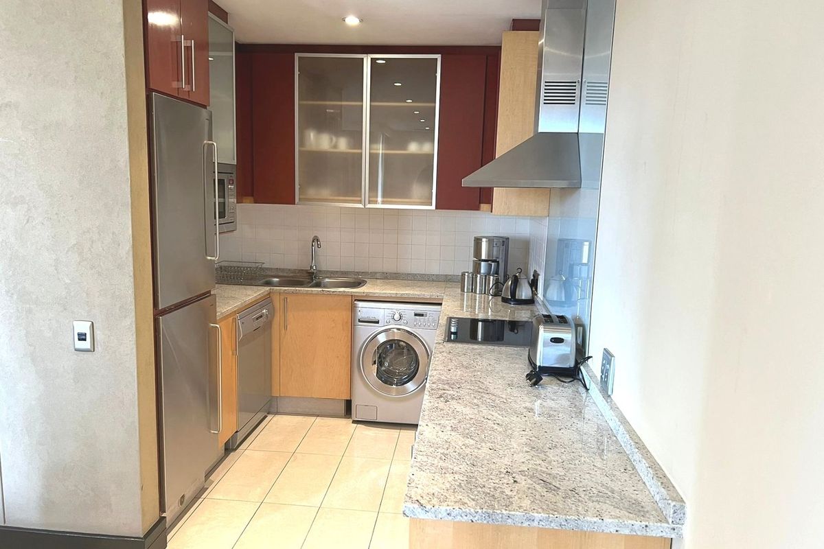 Compact kitchen featuring granite countertops, stainless steel appliances, integrated cabinetry, and tiled flooring in a functional layout.