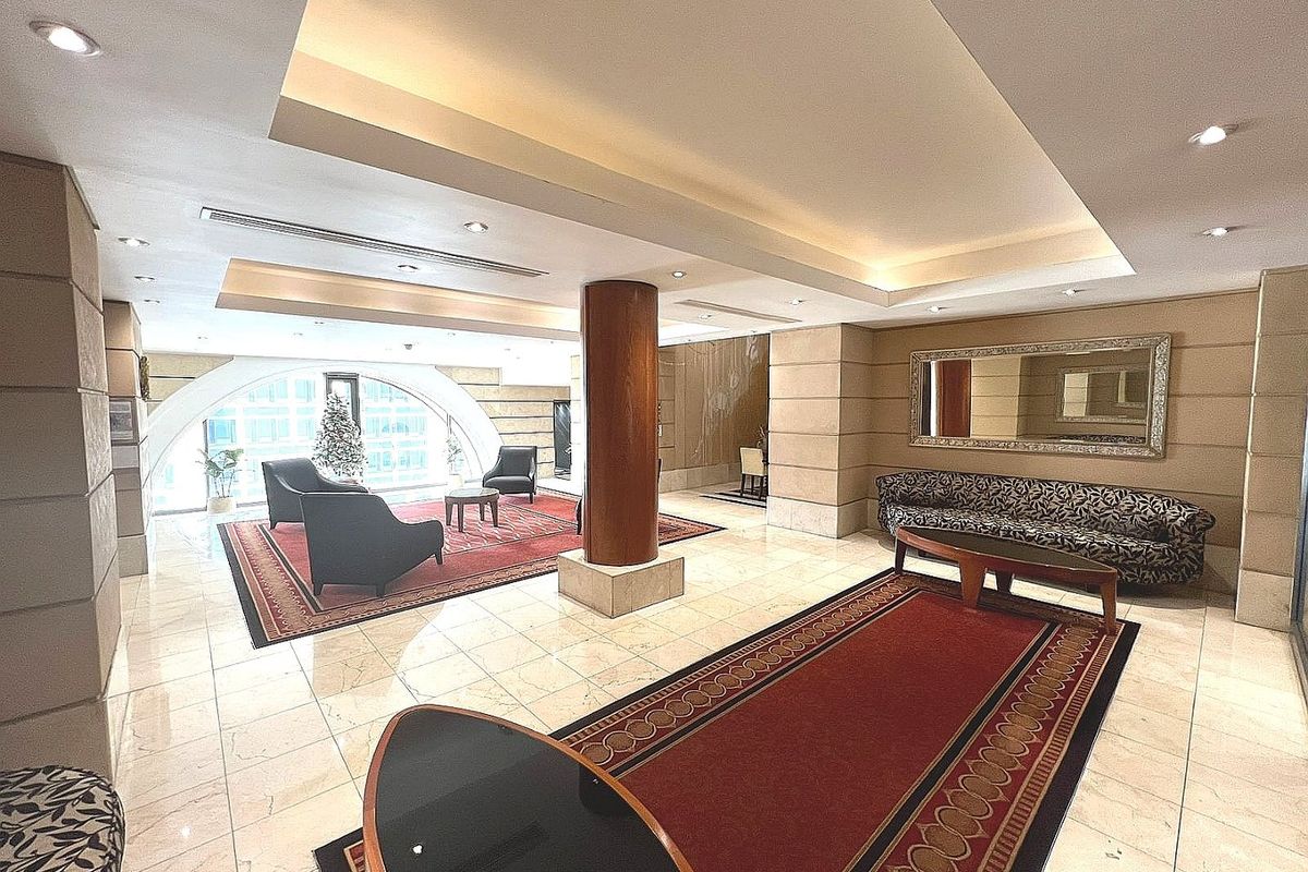 Spacious apartment lobby or living area featuring polished marble flooring, recessed ceiling lighting, and a prominent structural column.