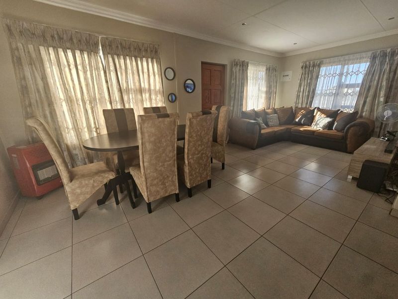 Spacious open-plan living and dining area featuring neutral tiled flooring, recessed lighting, and large windows with natural light.