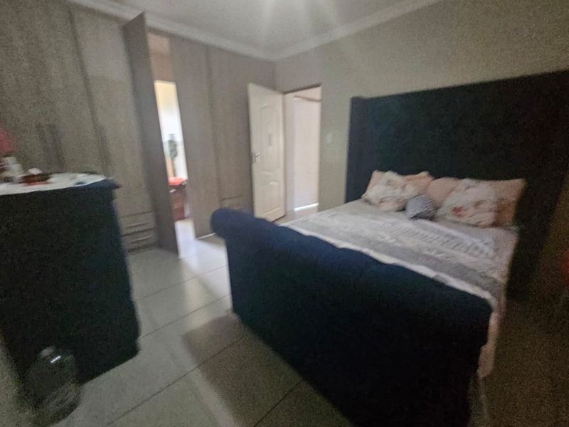 A bedroom featuring built-in cupboards and tiled flooring, providing a functional space with direct access to an adjoining room.