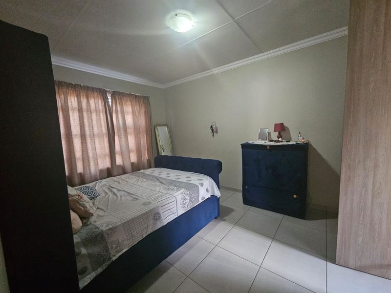 A functional bedroom featuring tiled flooring, neutral wall finishes, and a flush mount ceiling light, providing a clean and simple living space.