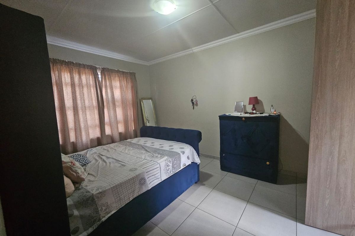 A functional bedroom featuring tiled flooring, neutral wall finishes, and a flush mount ceiling light, providing a clean and simple living space.