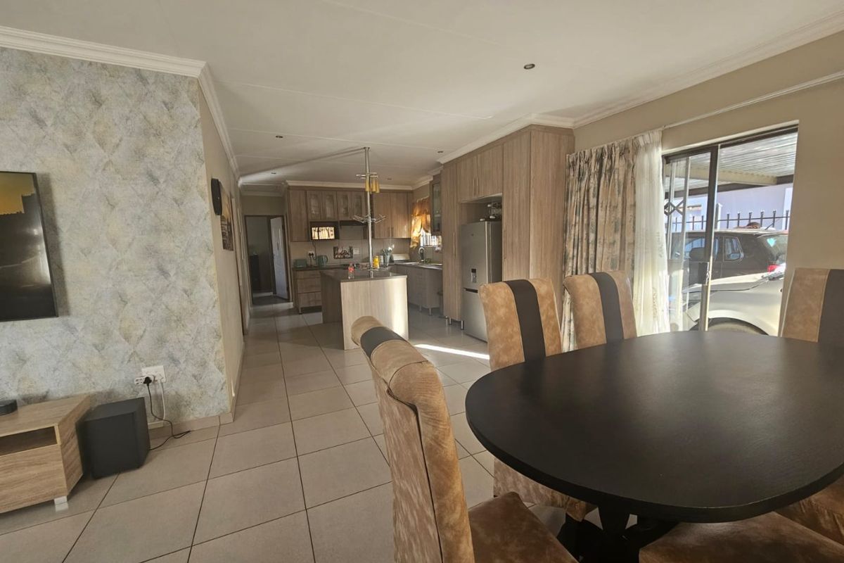 Open-plan living and dining area featuring tiled floors, modern kitchen cabinetry with an island, and direct access to the exterior via a sliding door.