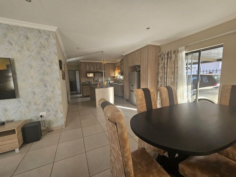 Open-plan living and dining area featuring tiled floors, modern kitchen cabinetry with an island, and direct access to the exterior via a sliding door.