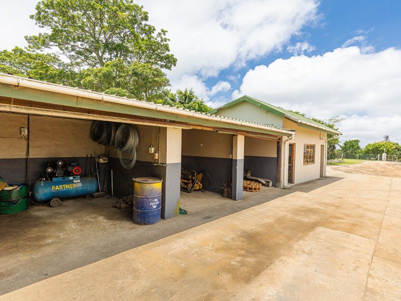 An open-bay farm garage or utility structure featuring concrete flooring and a corrugated metal roof, suitable for equipment storage or workshop use.
