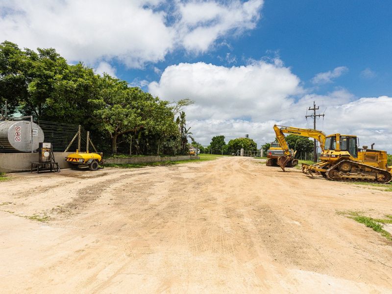 An open farm utility area featuring a fuel storage tank, perimeter fencing, and access to the property grounds.