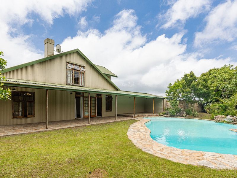 Rear view of a farm-style residence featuring corrugated metal cladding, a spacious covered patio, and a landscaped swimming pool area.