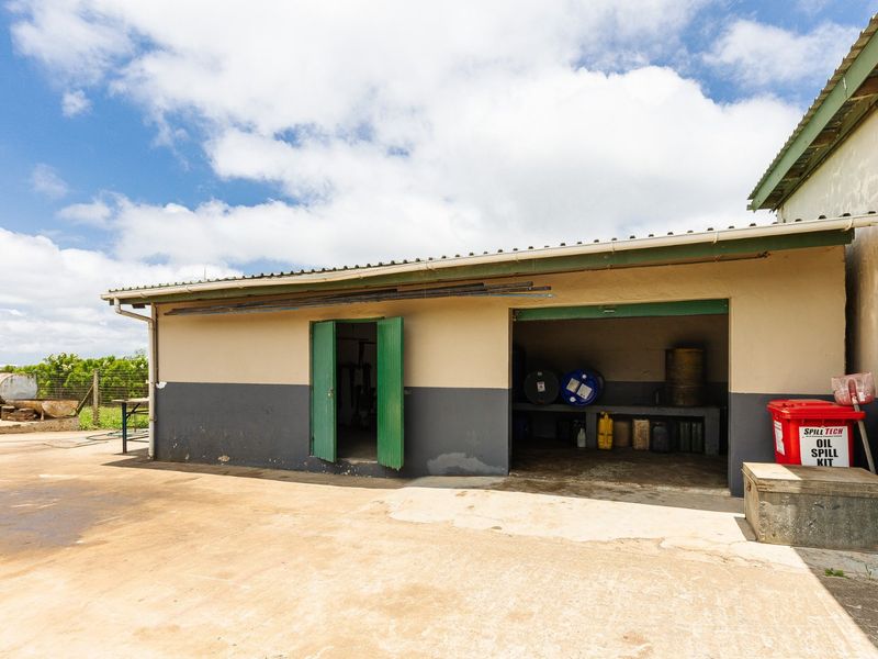 A functional farm utility shed featuring a concrete apron, built-in workbench, and durable metal doors, suitable for storage or workshop activities.