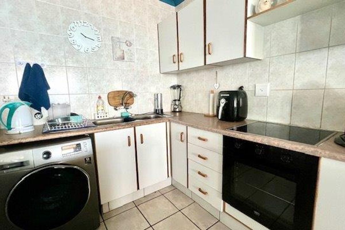 A functional kitchen featuring built-in cabinetry, laminate countertops, a tiled splashback, and integrated cooking appliances, offering a practical layout for daily use.