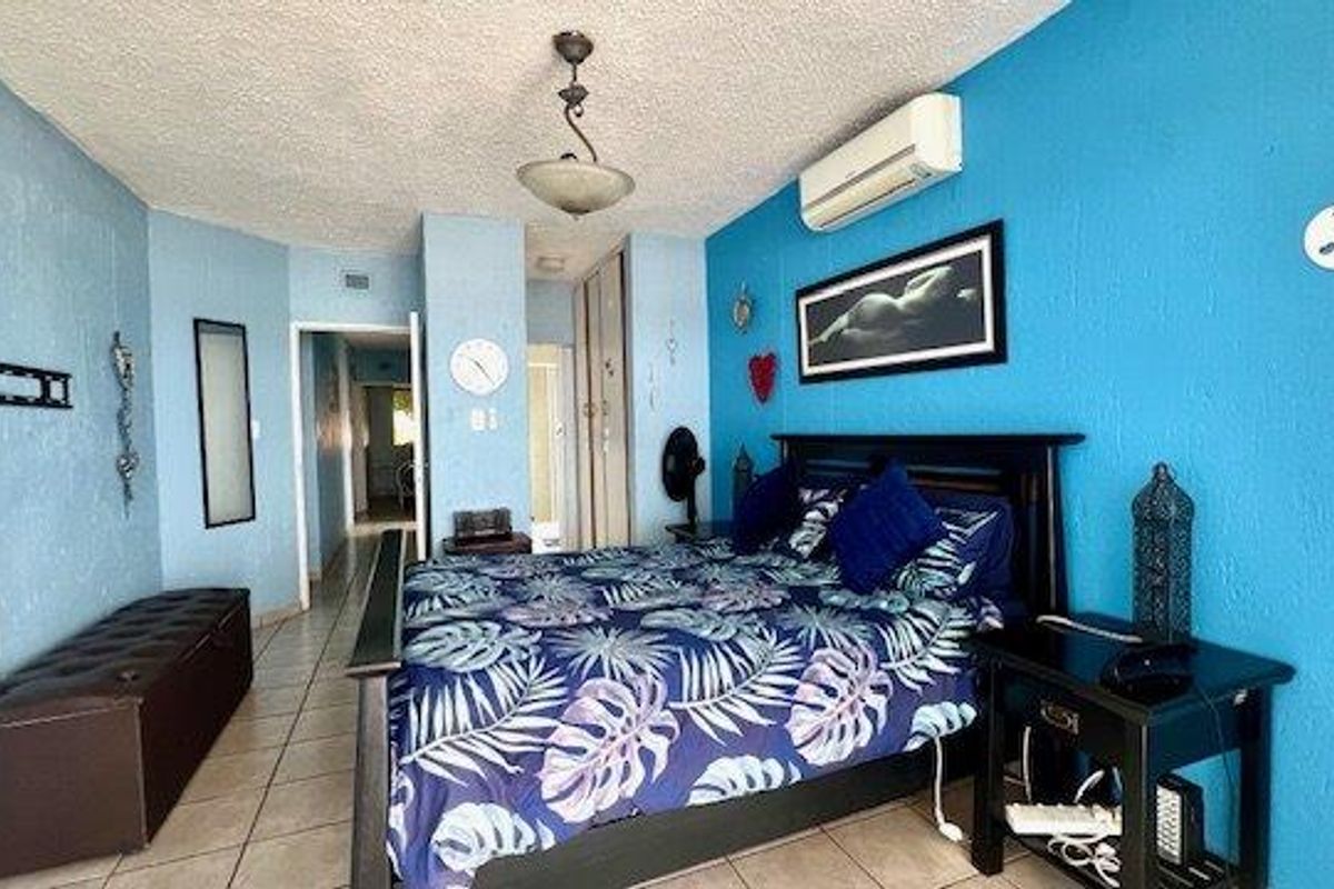 A bedroom featuring tiled flooring, built-in cupboards, and a wall-mounted split-system air conditioner.