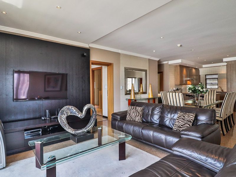 Spacious open-plan living and dining area featuring a modern kitchen with built-in cabinetry, recessed lighting, and tiled flooring throughout.