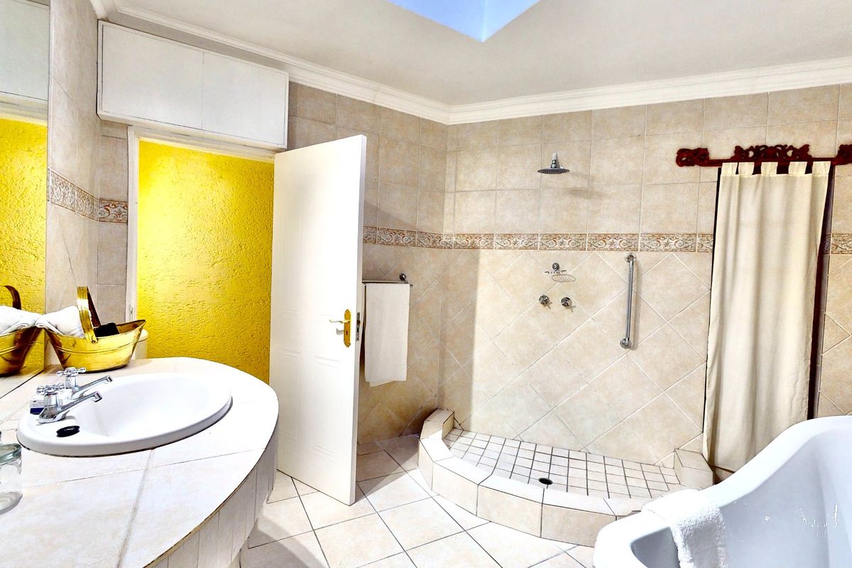 A functional bathroom featuring a tiled shower enclosure, built-in vanity, and a skylight, offering a dated but practical layout.