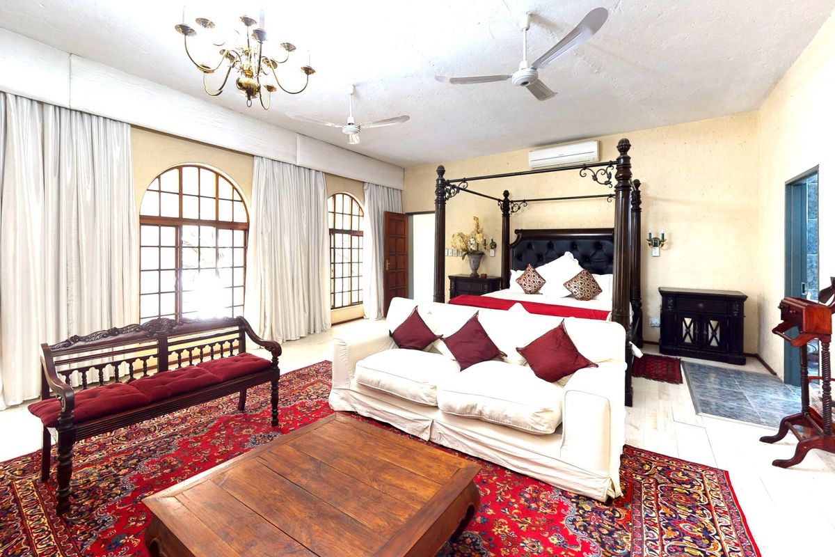 Spacious bedroom featuring arched windows, tiled flooring, and a wall-mounted air conditioning unit.