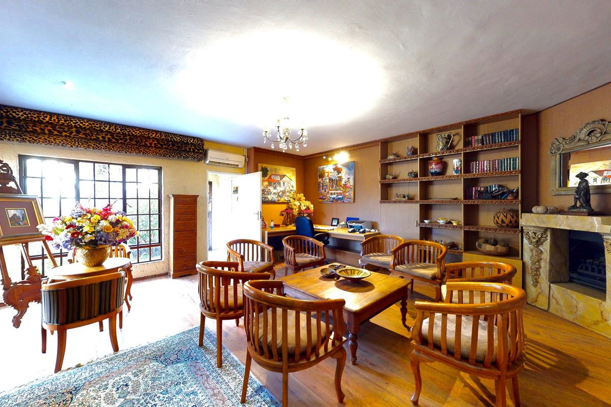 Spacious living area featuring built-in wooden shelving, a decorative fireplace with an ornate mantel, and hardwood flooring.