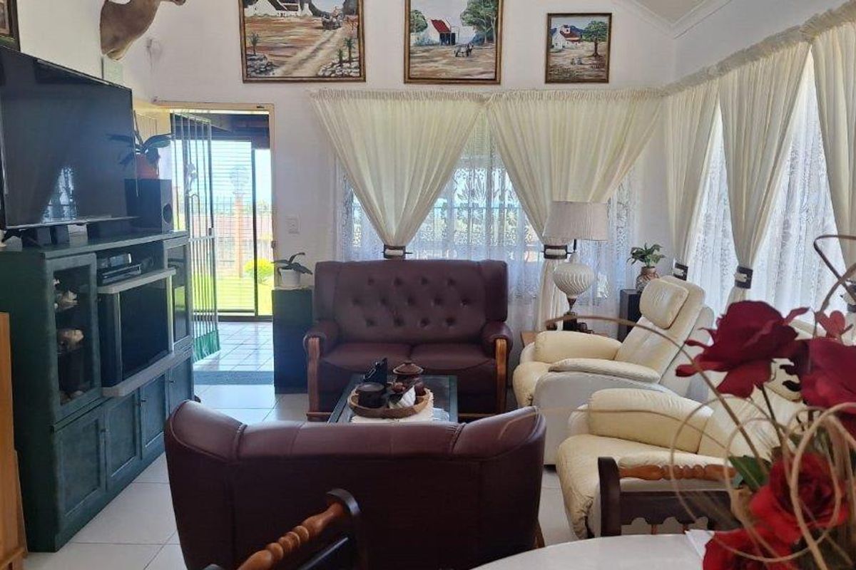 A comfortable living room featuring tiled flooring, a vaulted ceiling, and direct access to an outdoor area through a security gate.