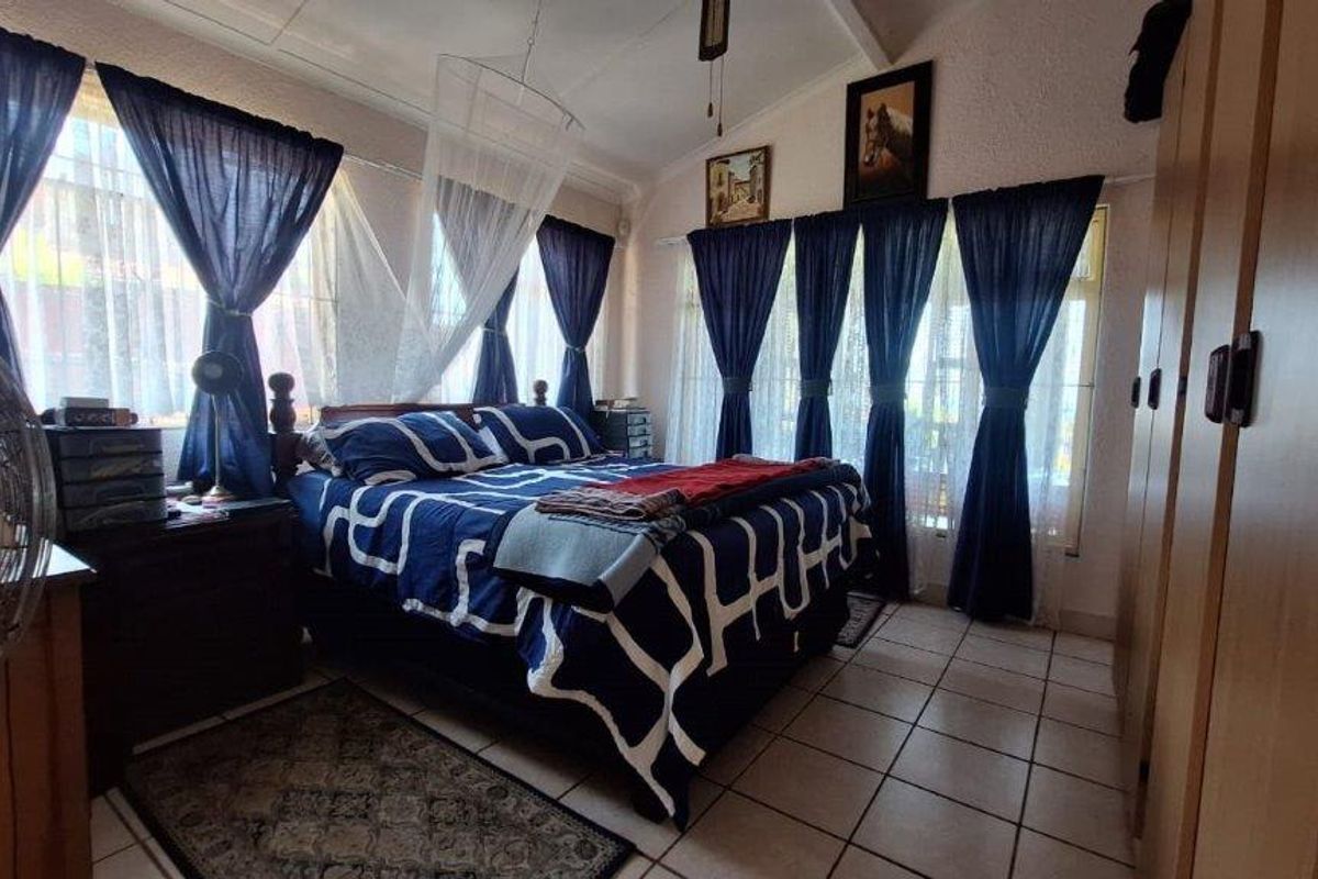 A bedroom featuring tiled flooring and built-in cupboards, offering a functional space with natural light.