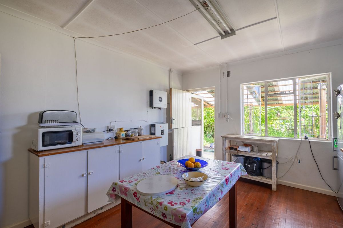 A functional kitchen area featuring timber flooring, built-in cabinetry, and a stable door leading to the exterior, with an integrated solar inverter system.