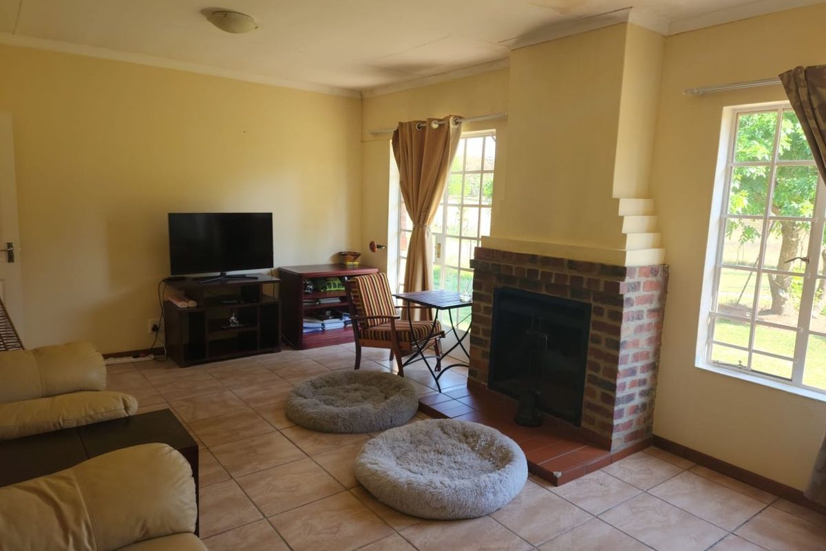 Living room featuring a traditional brick fireplace, tiled flooring, and natural light through large windows with access to the exterior.