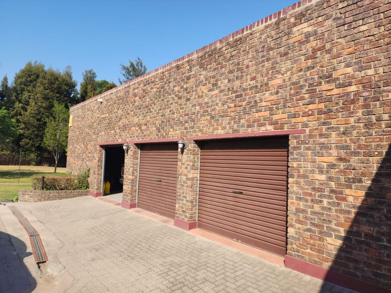 A triple garage featuring face brick construction and secure roller doors, situated on a paved driveway.