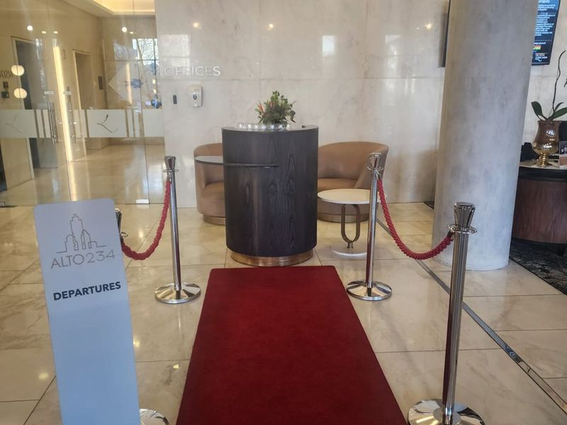 Modern apartment building entrance lobby featuring polished marble flooring, a structural concrete column, and glass partition doors.
