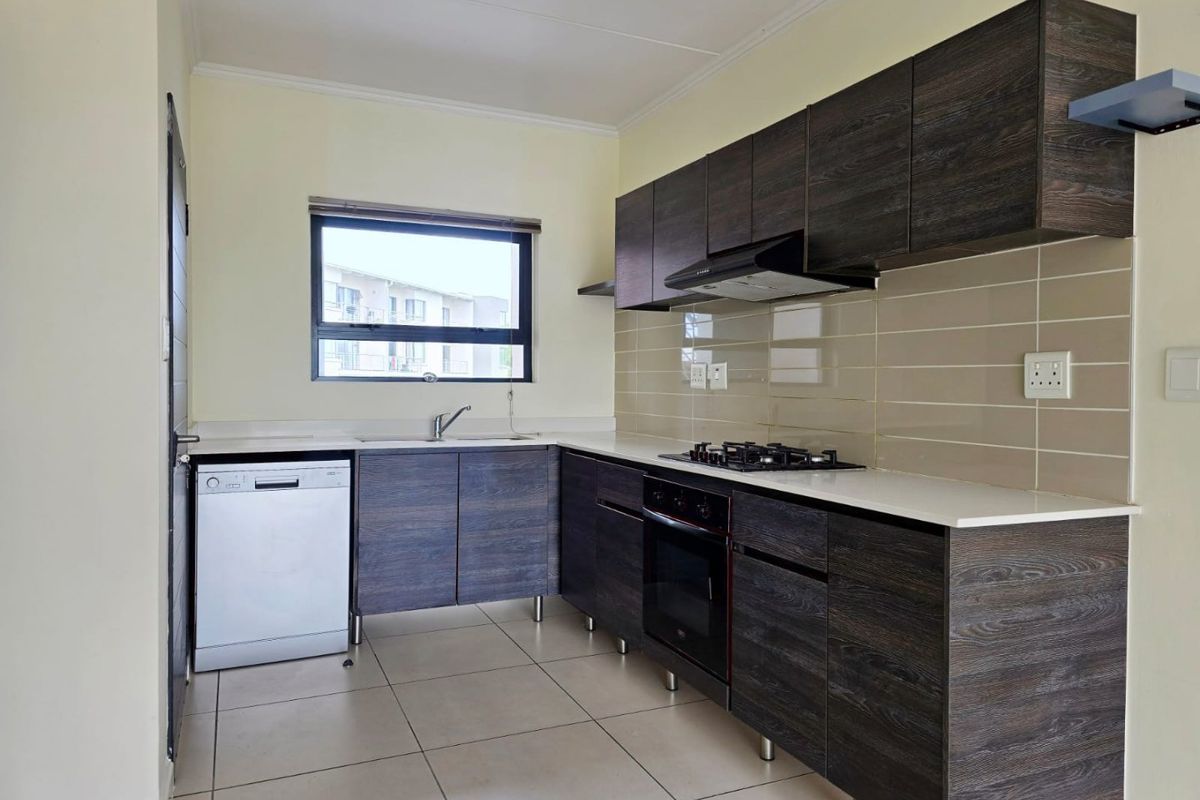 Modern kitchen featuring dark wood-grain cabinetry, stone-look countertops, a gas hob, built-in oven, extractor fan, and tiled backsplash.