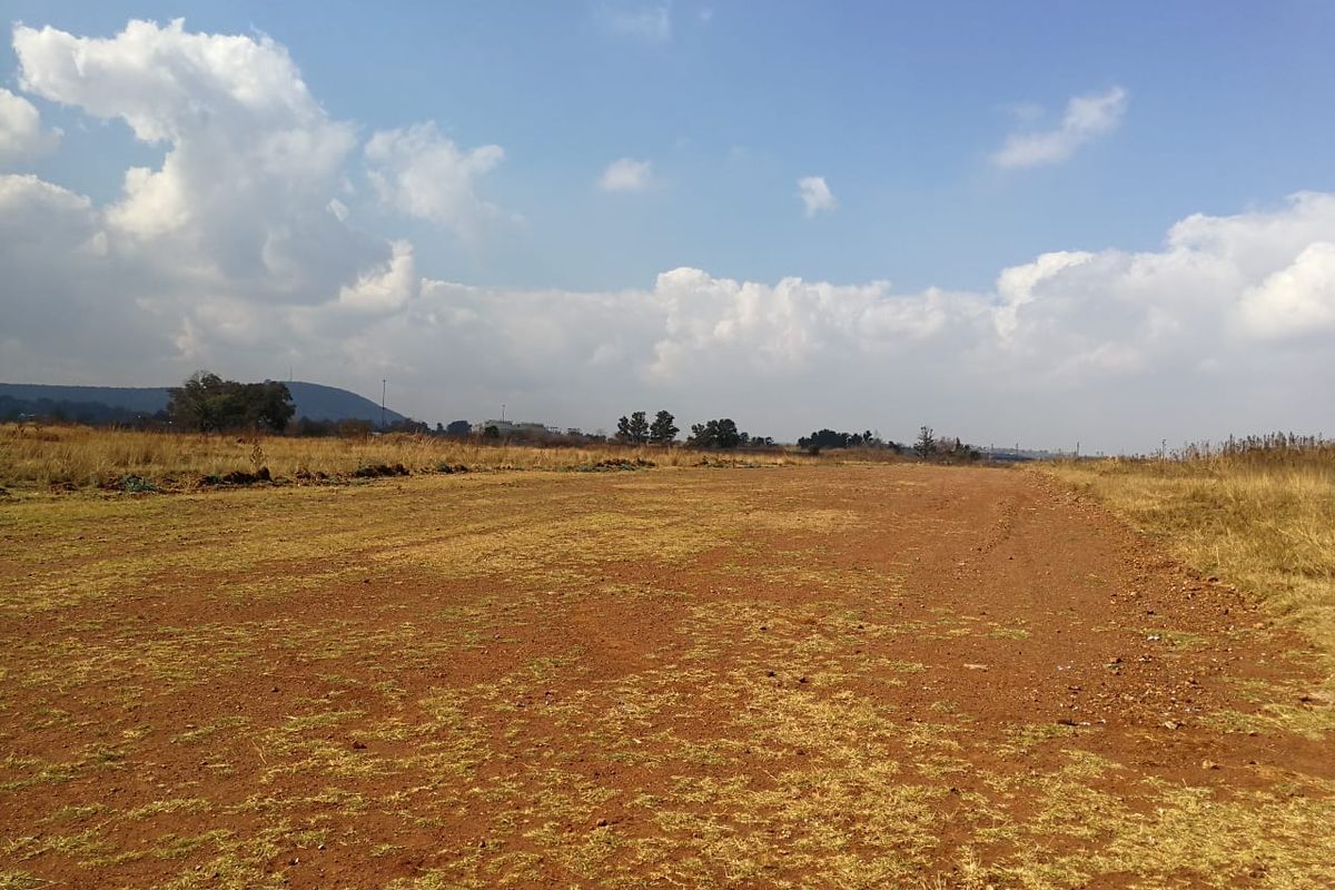 A wide-angle view of a vacant residential plot featuring natural terrain and open landscape.