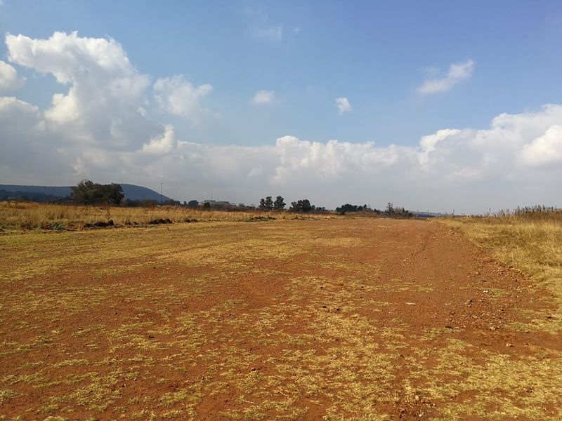 A wide-angle view of a vacant residential plot featuring natural terrain and open landscape.