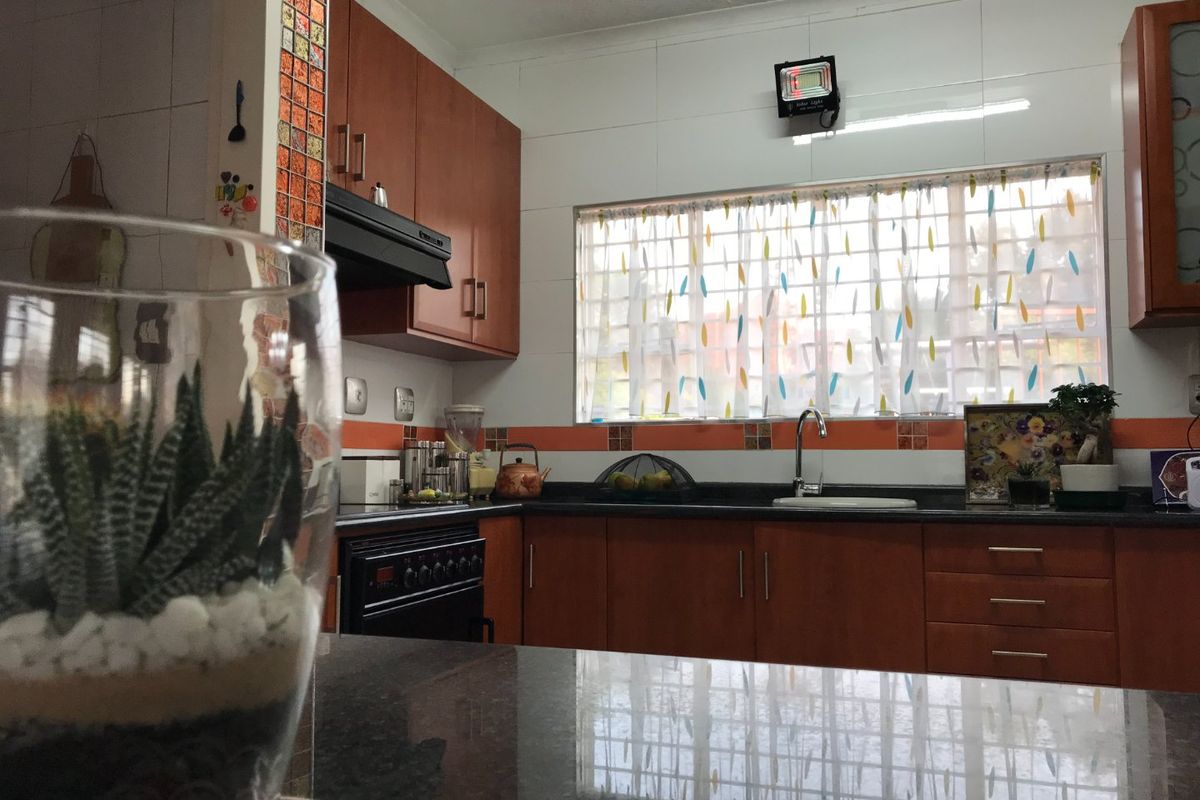 A functional kitchen featuring wood-toned cabinetry, dark granite countertops, a built-in oven, and a stainless steel sink with tiled backsplash.