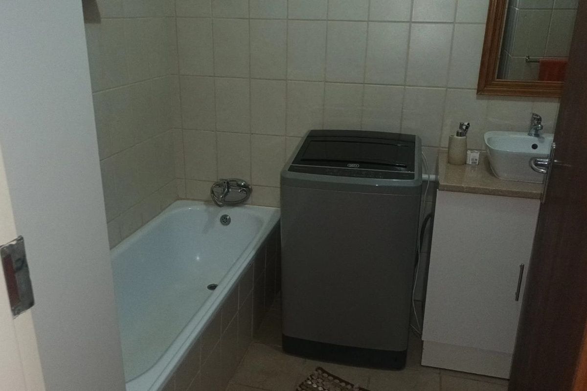 A functional bathroom featuring a bathtub, vanity cabinet with basin, and tiled wall finishes.